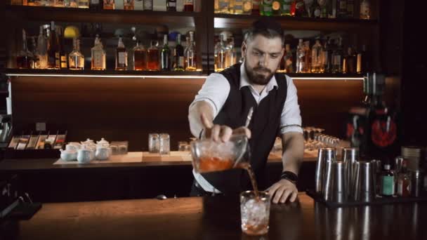Il barista del bar versa un cocktail rosso-arancio in un bicchiere di ghiaccio. — Video Stock