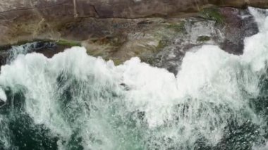 Hava görüntüsü soyut çok renkli okyanus dalgaları desenli kayaya çarpıyor. 