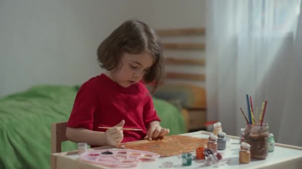 Das Mädchen am Kindertisch sitzt und malt. — Stockvideo