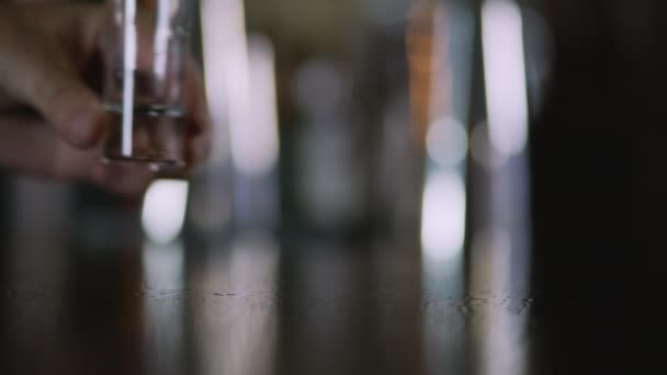 Чоловіча рука кладе склянку на стіл . — стокове відео
