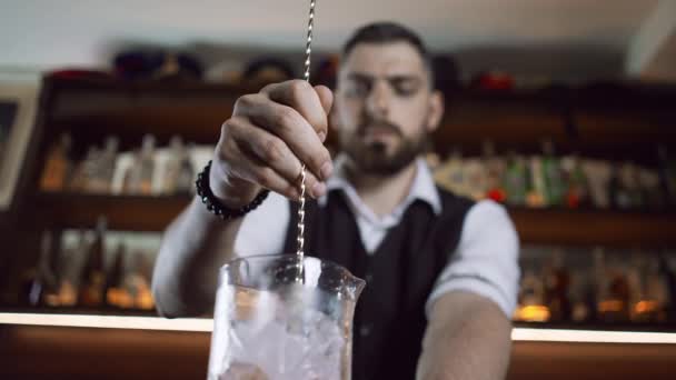 De barman aan de bar bereidt een drankje met een barlepel. — Stockvideo