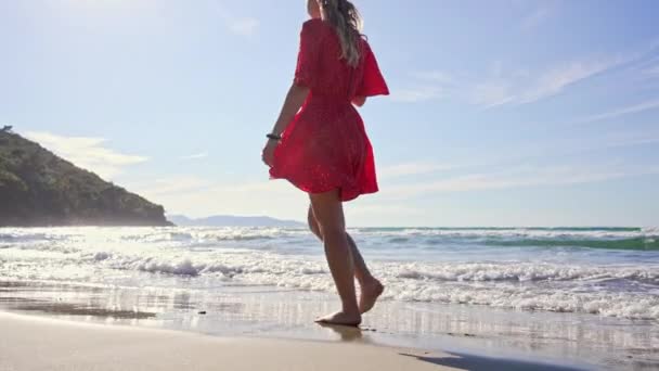 Vrouw op het strand die over het water loopt. — Stockvideo