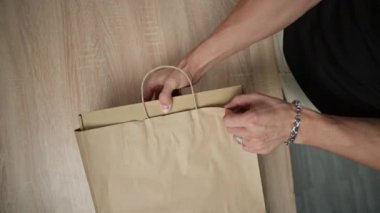 El, mutfak masasının üzerinde organik bir top olan bir kağıt kutu çıkarıyor.