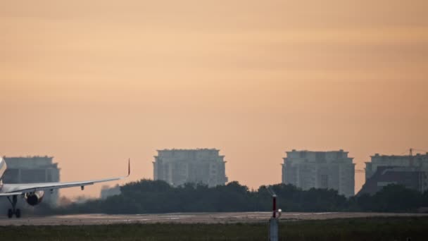 Paisaje urbano al amanecer en la mañana en la que despega un avión de pasajeros — Vídeos de Stock