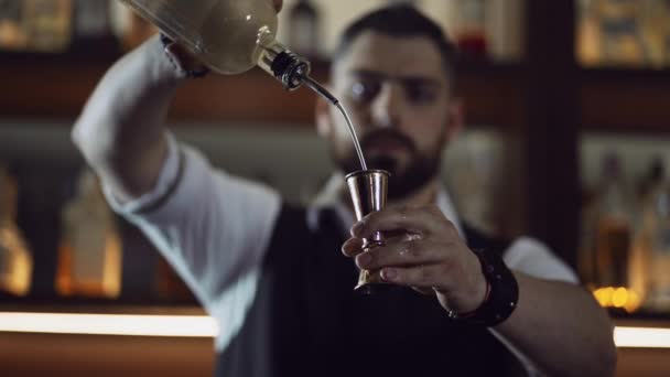 Cantinero en el bar vierte el ingrediente del cóctel en una taza de medir - jigger — Vídeos de Stock