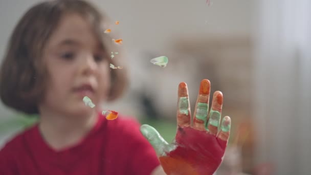 Белая девушка кладет свои отпечатки на стекло с краской. — стоковое видео