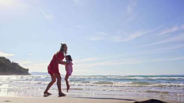 Dziewczynka biegnie po plaży w ramionach do mamy. — Wideo stockowe