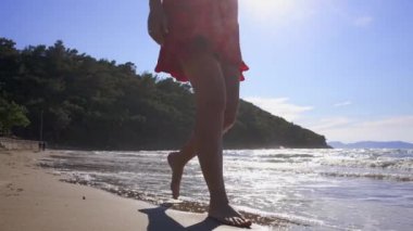 Güzel kadın bacakları kumlu sahilde yürüyor.