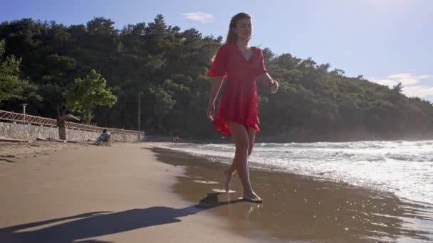 Belle fille dans une robe rouge aime marcher pieds nus sur l'eau — Video