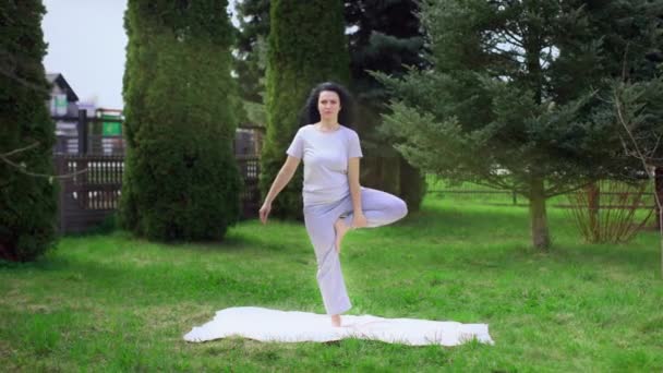 The girl is doing yoga in the garden. Healthy lifestyle — Wideo stockowe