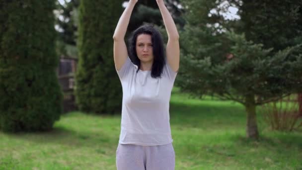 European woman practices yoga in the garden alone.