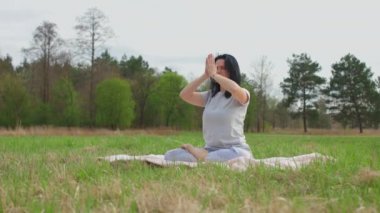 Doğada meditasyon yapan bir kız, ağaçlı bir çimenlikte