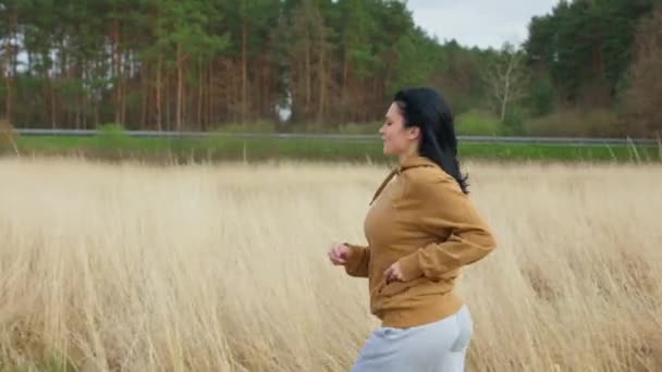 Caucasian girl jogging in the field. Woman running — Stock Video