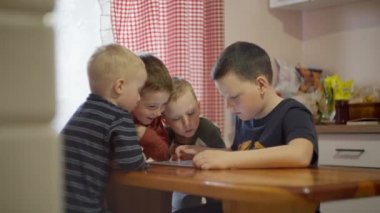 A group of Caucasian boys sitting on the Internet on a tablet. 