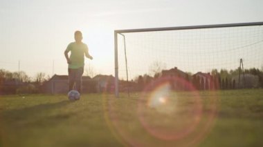 Delikanlı futbol topuyla koşuyor, futbol kalesine yakın yeşil alanda.. 