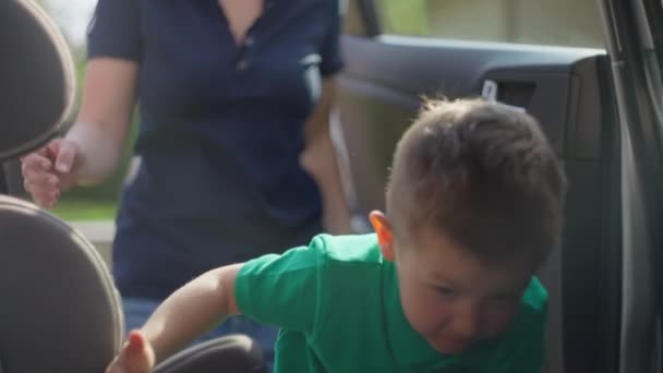 Niño feliz se mete en un asiento de coche para niños — Vídeos de Stock