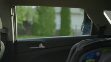 Mom puts a little girl in a child seat in the car. 