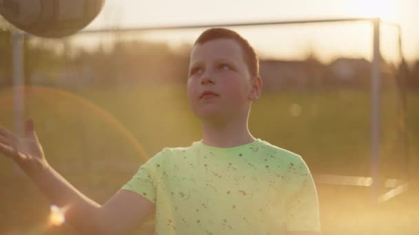 Boy holding a ball in his hands with a beautiful sunny flu. — Wideo stockowe