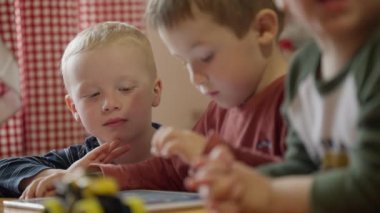 Three boys play games on a tablet. 