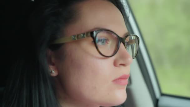 Beautiful Caucasian girl with glasses is driving a car. — Wideo stockowe