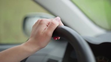Direksiyondaki kadın elinin yakın çekimi. Kız seyahat ederken araba kullanıyor..