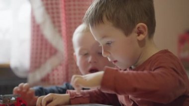 Boys kids playing games on tablet at home in the kitchen. Caucasian children 