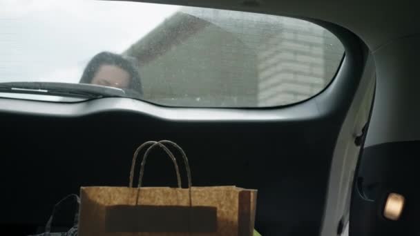 Жінка підбирає сумки з багажника автомобіля . — стокове відео
