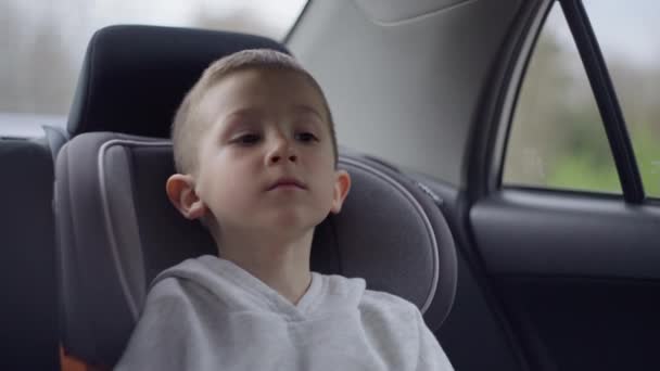 Ταξιδεύοντας παιδί κάθεται σε ένα κάθισμα αυτοκινήτου. — Αρχείο Βίντεο