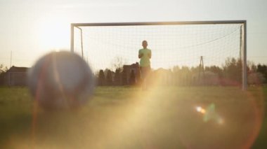 Kapıda duran bir çocuk topu yakalıyor. Çocuk futbol oynuyor..