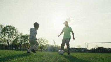 Çocuklar çimlerin üzerinde futbol oynuyor. Çocuklar futbol maçında antrenman yapıyor, gol atan mutlu çocuklar..
