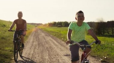 Aile birlikte doğada bisiklet sürerek zaman geçirir. Parkta bisiklet süren kadın ve çocuk güzel bir manzaraya sahipler..