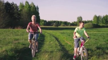 Anne ve bebek tarlada bisiklet sürüyor. Güzel doğa ve aile parkta spor ve eğlenceyle meşgul..