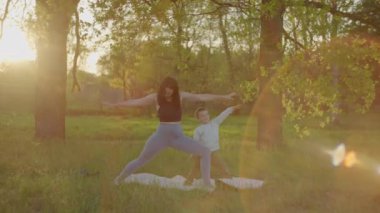 Kafkas anne ve oğlu parkta yoga yapıyorlar. Çocuk ebeveynleriyle yoga asanas yaparak zaman geçiriyor. Yetişkinler ve çocuklar için aerobik, aile birlikte mutlu..