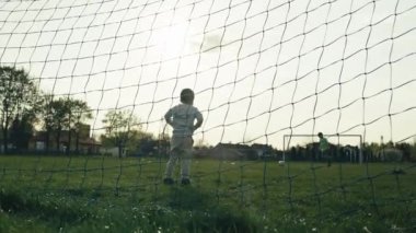 Çocuk futbol kalesinde duruyor ve toptan korkuyor. Çocuklar stadyumda futbol oynuyorlar. Takım oyunu ve mutlu aktif bir çocukluk..