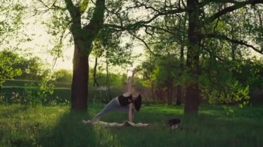 Doğayla baş başa. Gün batımında parkta yoga pozu veren bir kız. Kadın çimenlerin üzerinde sis yapıyor..