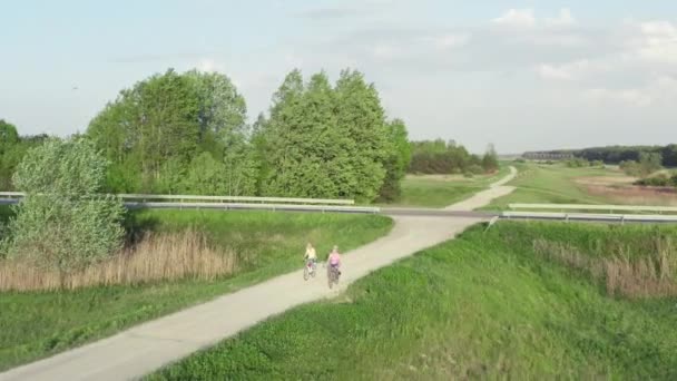 两个漂亮的女孩骑自行车在美丽的风景里 在阳光充足的天气里 女人喜欢在公园里积极地骑车 — 图库视频影像