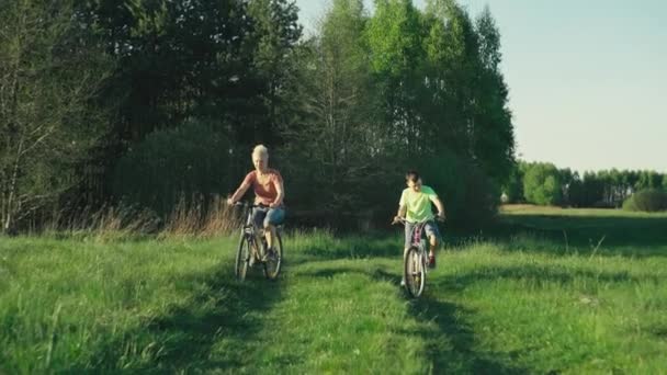 妈妈和儿子骑自行车在公园里 美丽的大自然 草木和孩子们与父母共度着欢乐和欢乐的时光 过着生活 — 图库视频影像
