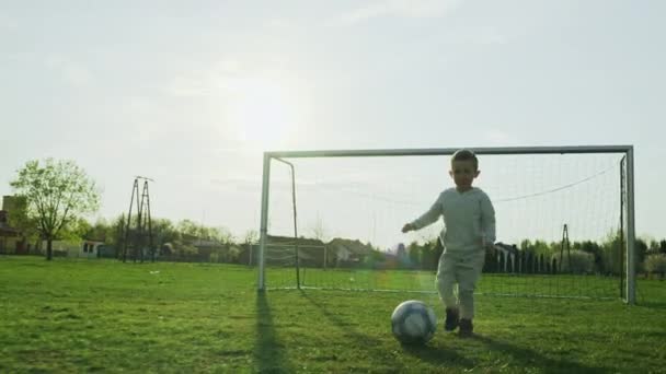 孩子在踢足球时拿着球跑 男孩在训练中以脚带球 这是一个慢动作的生活方式视频 来自一个快乐的体育童年 — 图库视频影像