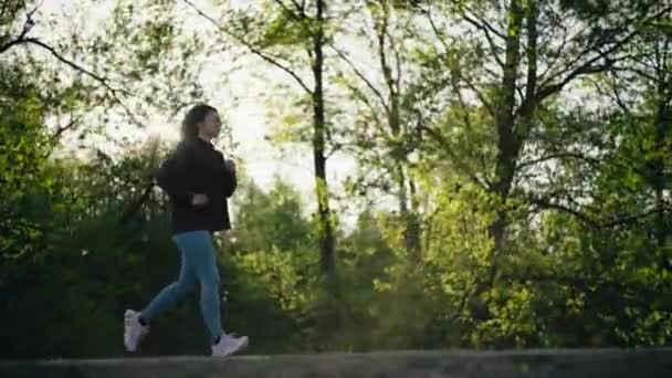 女人在公园里慢跑 日落时 那姑娘在路上奔跑 自然界中的树 积极的休闲生活方式和运动 — 图库视频影像