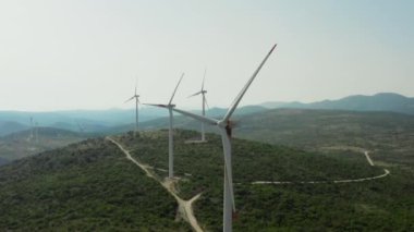 Dağlardaki endüstriyel yel değirmenlerinin havadan görünüşü. Rüzgar enerjisi üretimi, güzel bir manzara ve yel değirmeni bıçakları dönüyor..