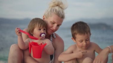 Büyükanne ve torunlar okyanus kıyısında sahilde birlikte oynuyorlar. Güzel bir manzarada deniz kenarında dinlenen mutlu bir aile..