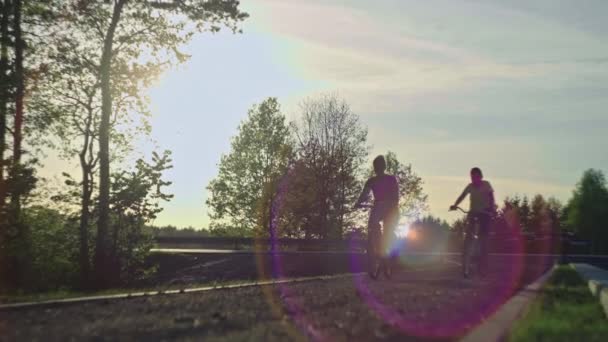 一个女人和一个男孩骑自行车在大自然中的轮廓 美丽的风景和家人一起在树林里骑车 — 图库视频影像