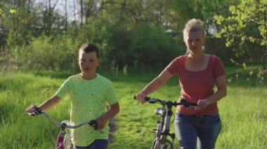 Yürüyüşten sonra parkta bisiklete binen anne ve oğul. Aktif aile eğlencesi ve spor birlikte..