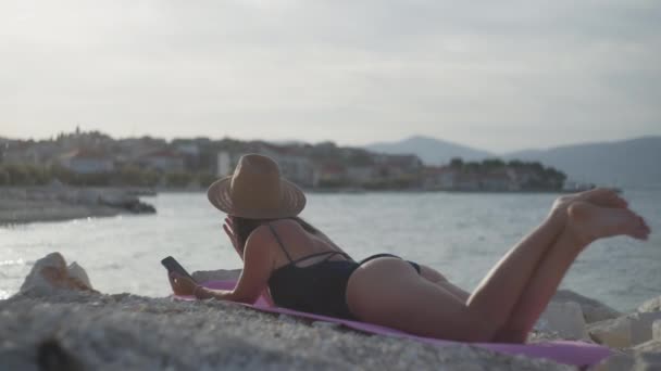 수영복을 소녀는 해변에 있으며 전화로 편지를 바다에서 휴가를 보내거나 여름철에 — 비디오