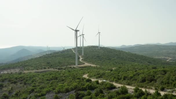 空中ビュー山の中で電気を発生させる風車 風車が立ち 風から電気を生み出す山脈の美しい風景 — ストック動画