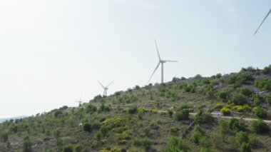 Hava manzaralı insanlar araba ile yel değirmenlerini geçiyor. Rüzgar enerjisi ve insanlardan ekolojik elektrik üretimi.