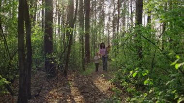 İki çocuklu bir anne ormanda yürür. Mutlu bir aile birlikte doğada vakit geçiriyor..