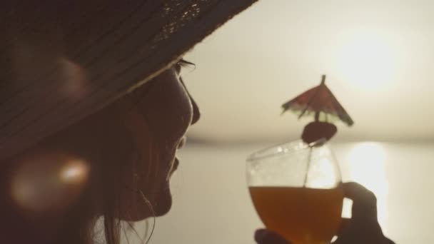 一个女孩在海边喝一杯鸡尾酒的特写镜头 日落和女人在海边喝着软饮料 享受度假时的风景 — 图库视频影像