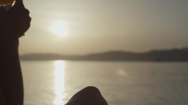 Gün batımında okyanusun kenarında bir zindanın elinde bir bardak kokteylin yakın çekimi. Serin bir hafta sonu ve deniz kenarında güzel bir tatil..