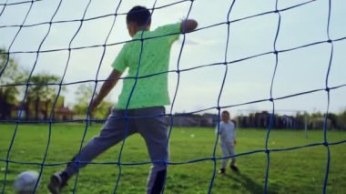 Çocuklar çimlerin üzerinde futbol oynuyor. Kapıda işaret fişeğini döven çocukların birlikte vakit geçirdiği, oyun oynayan çocukların yavaş çekim videosu..